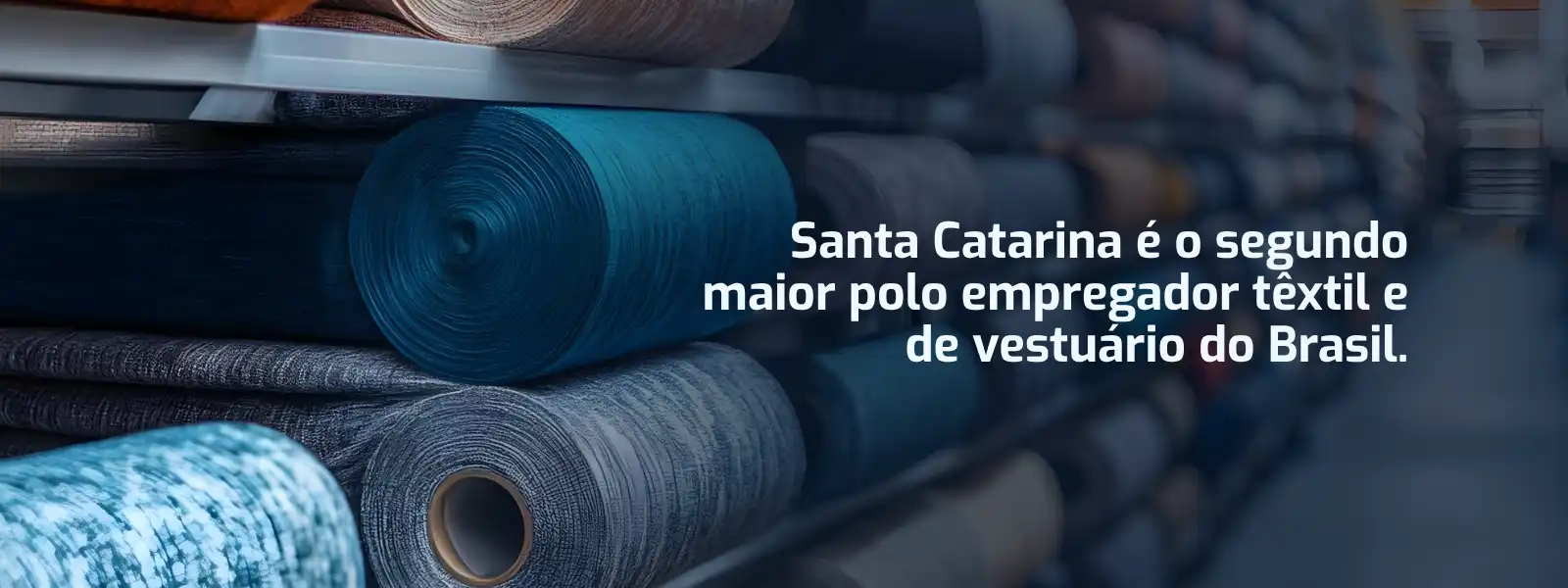 Banner do Senai Textil destacando Santa Catarina como o segundo maior polo têxtil e de vestuário do Brasil, com diversos rolos de tecidos ao fundo.